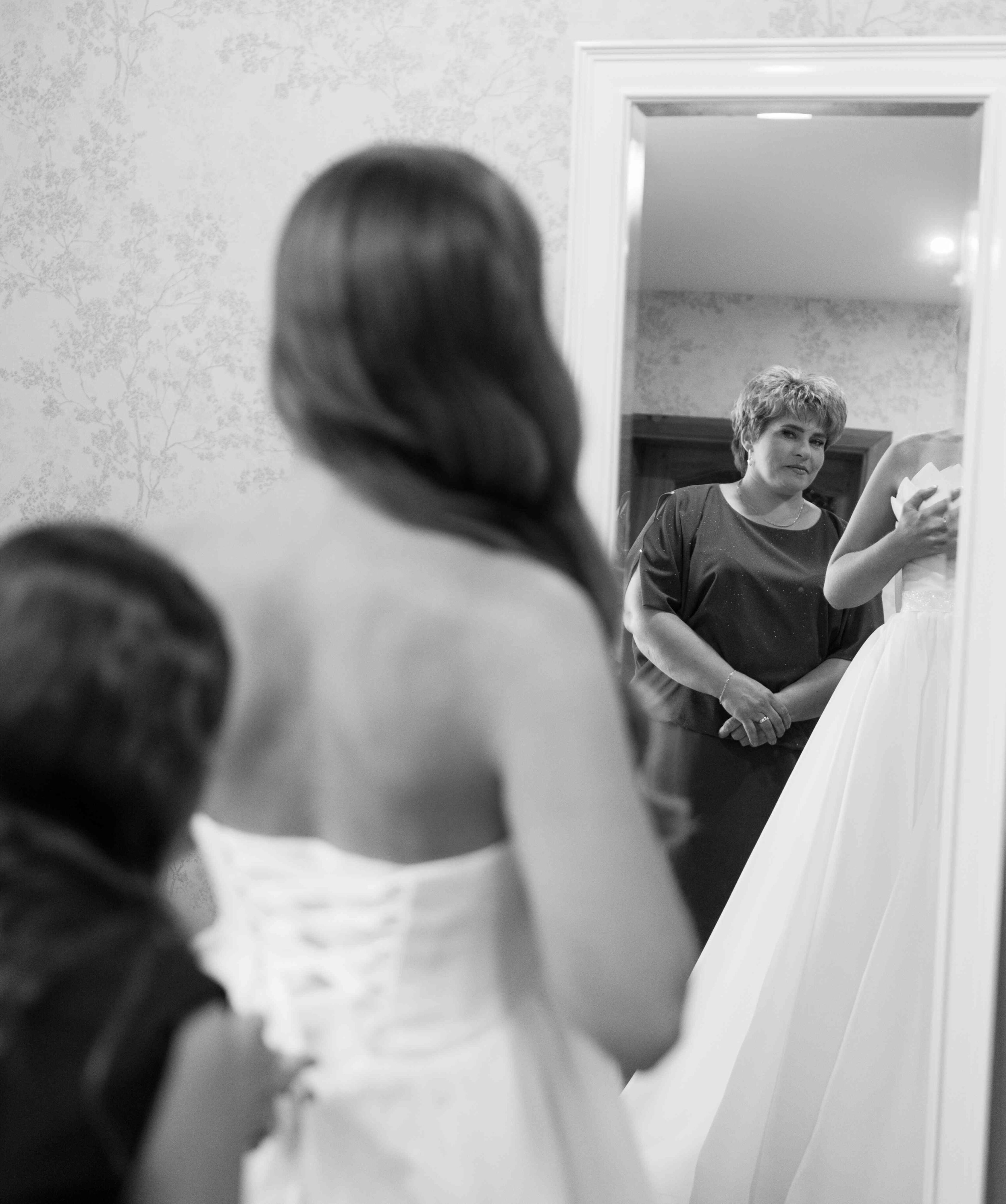 mother looking at bride daughter while preparing