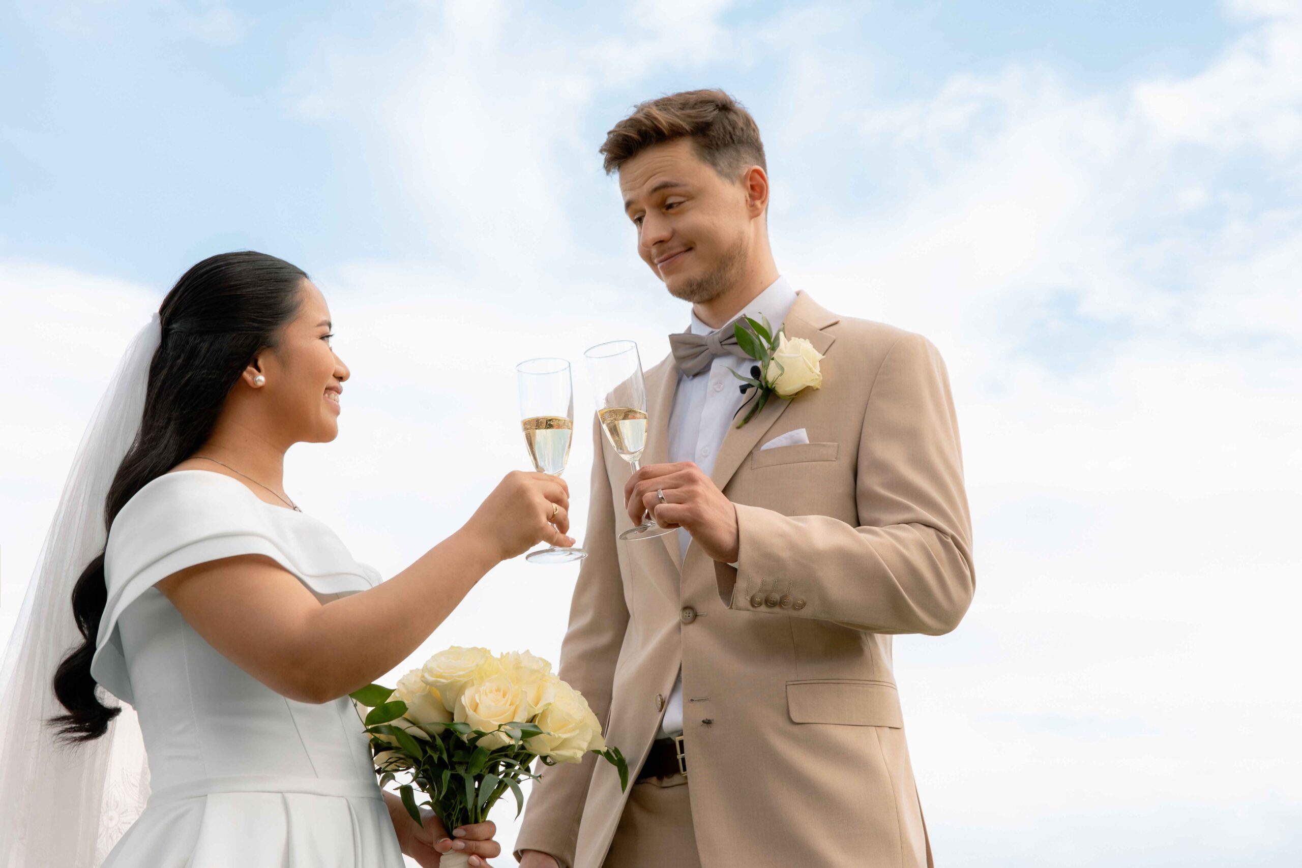 raising first glass after wedding ceremony blue sky
