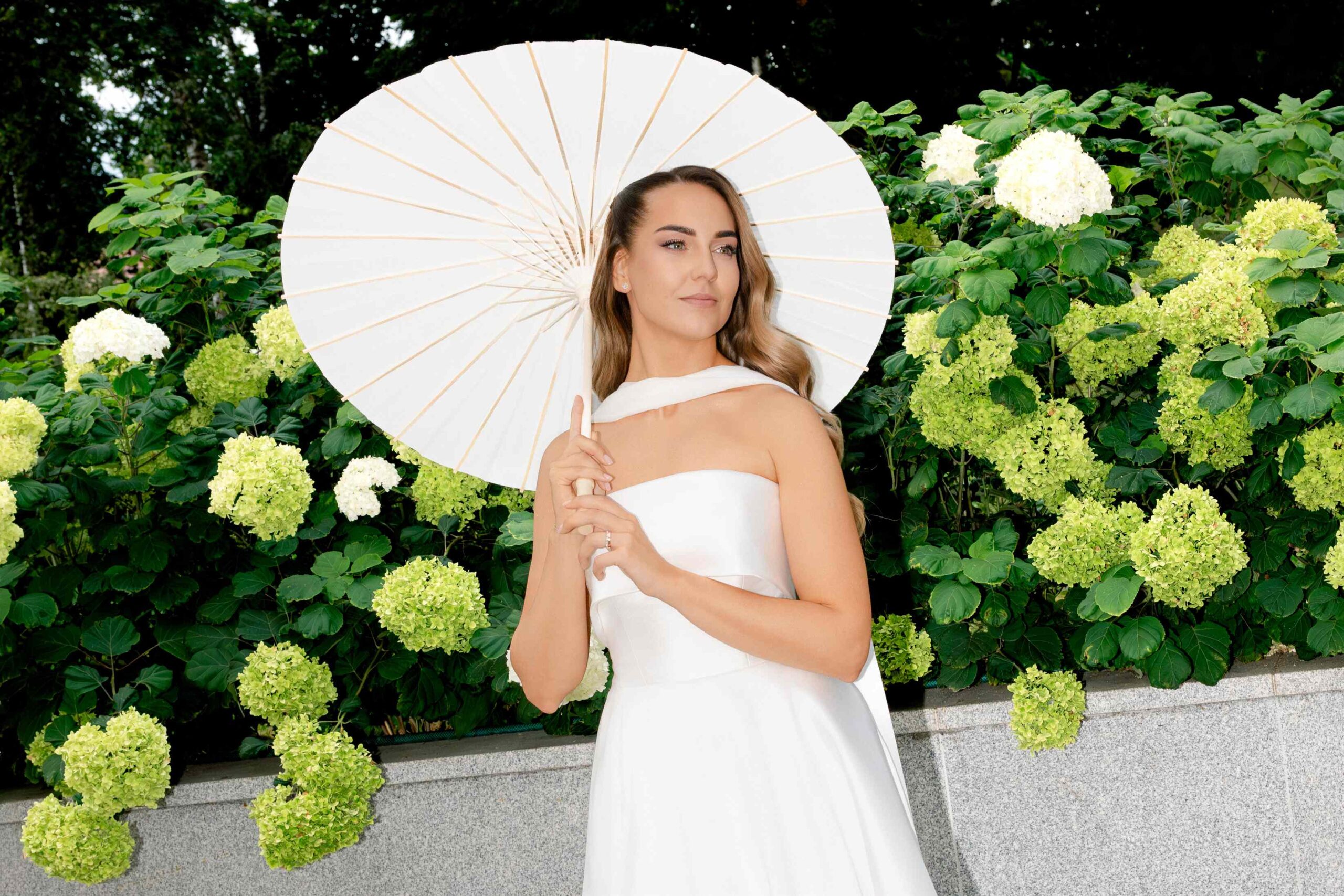 elegant bride portrait next to hydrangea plants flowers with paper umbrella