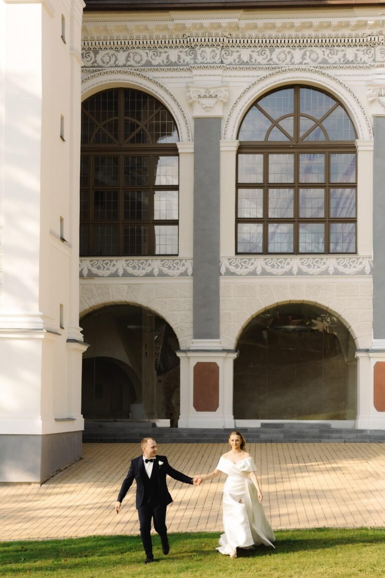 Bride and groom walking hand in hand in front of Sapiegos palace