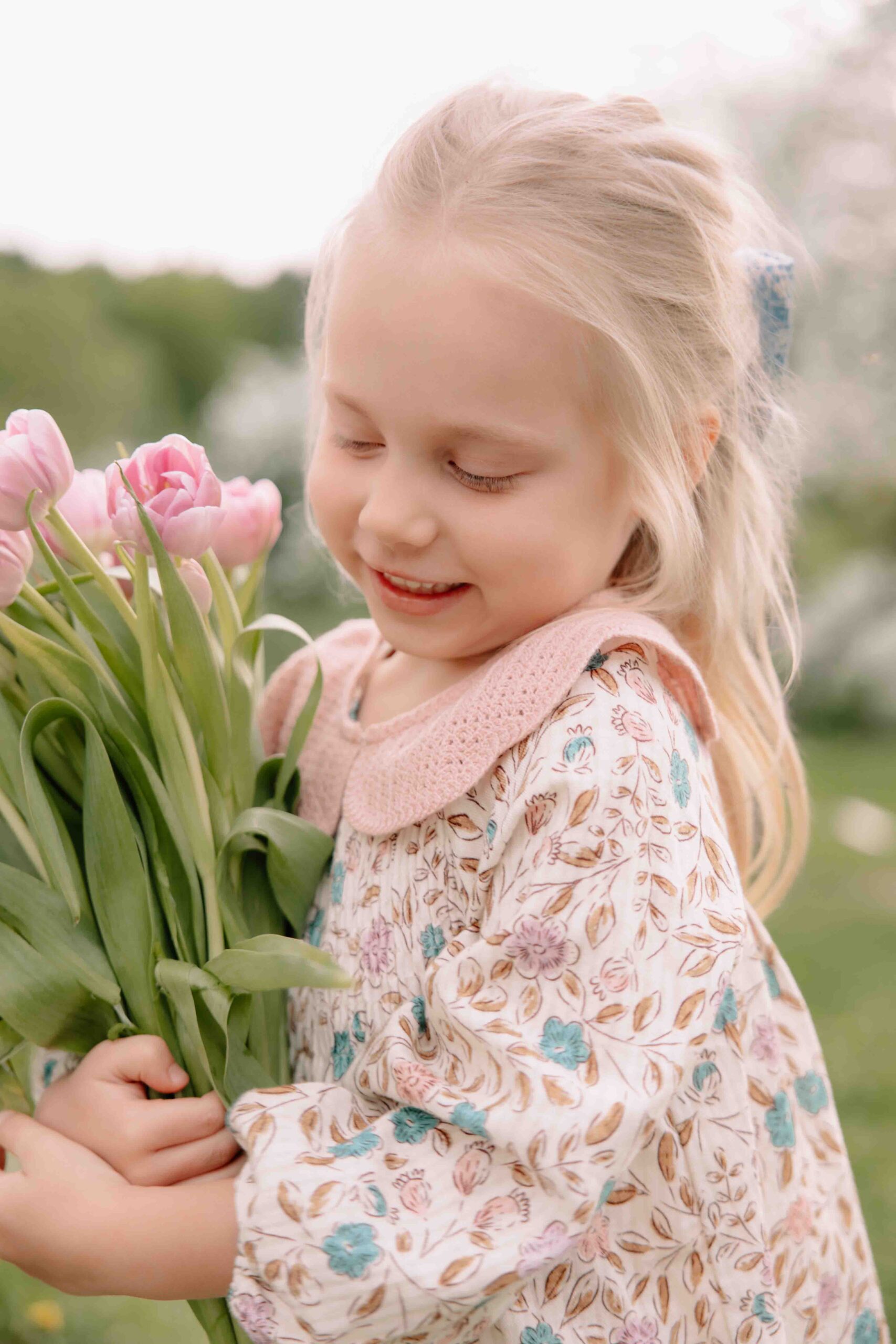 little cute blonde girl with flower dress and holding tulips blonde