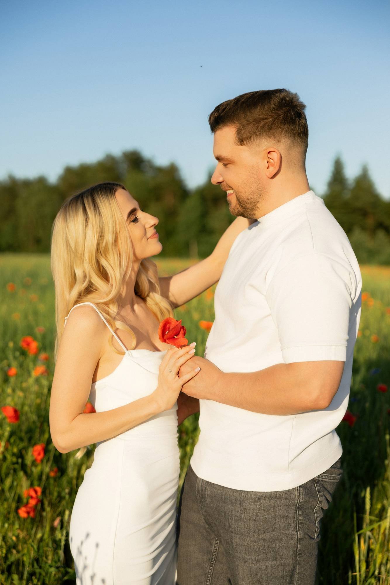 Couple standing face to face in a poppy field in Lithuania