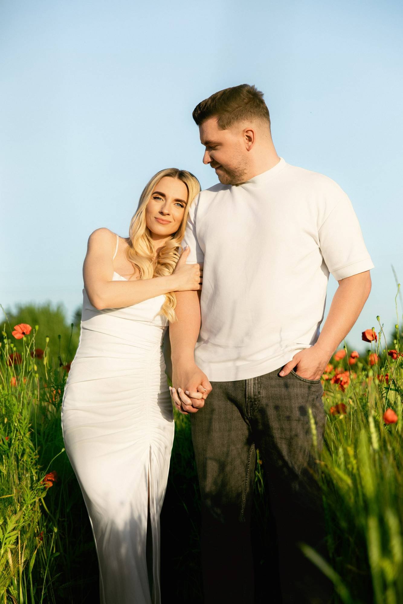 Woman leaning on her partner's shoulder while holding hands in a field