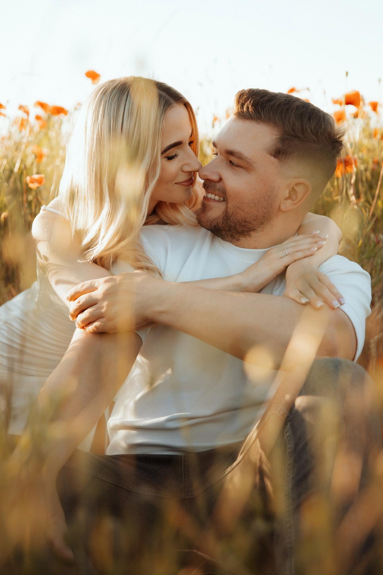 Couple hugging closely in golden hour light in a countryside field