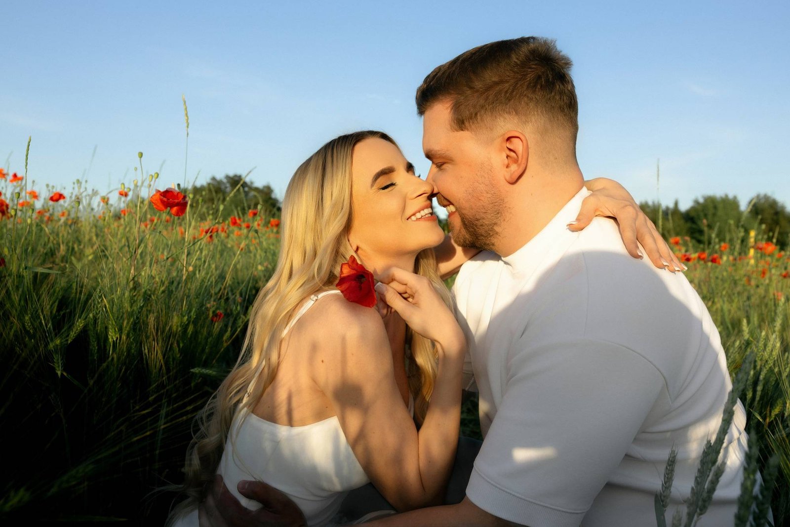 Couple nose to nose and smiling, woman wearing a poppy tucked behind her ear