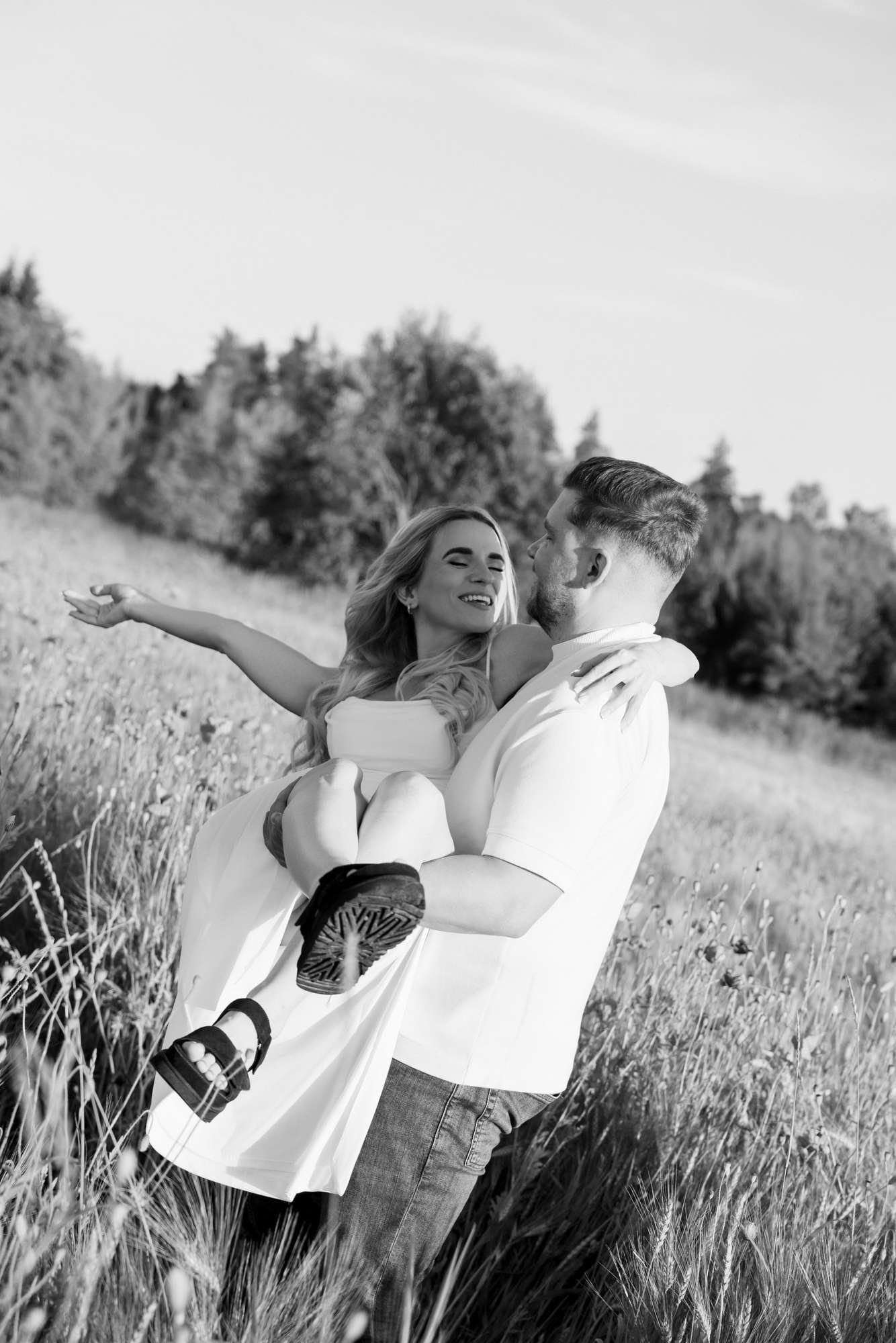 Man lifting his partner off the ground playfully, both laughing, black and white photo