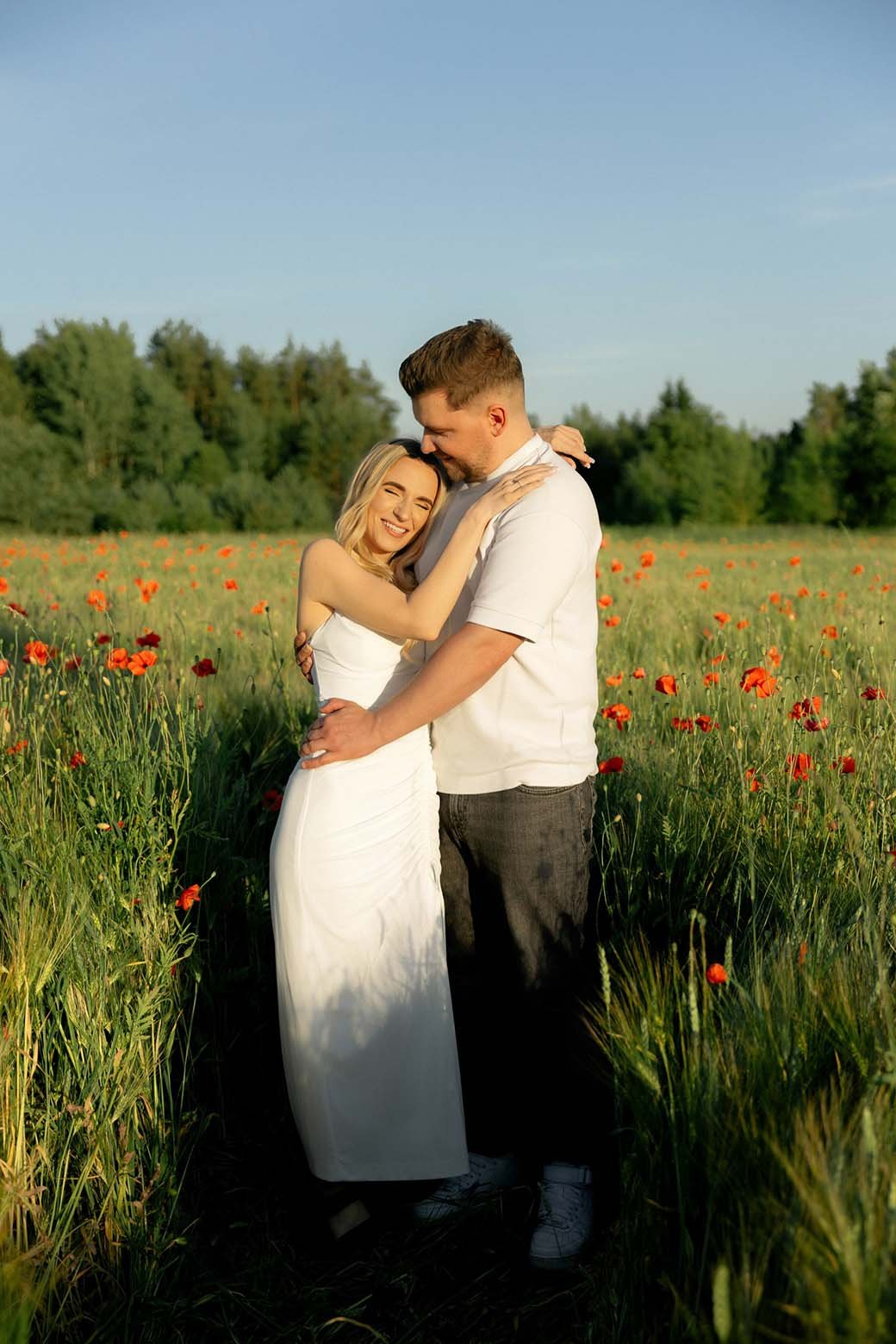 Engaged couple standing together in a poppy field in Lithuania
