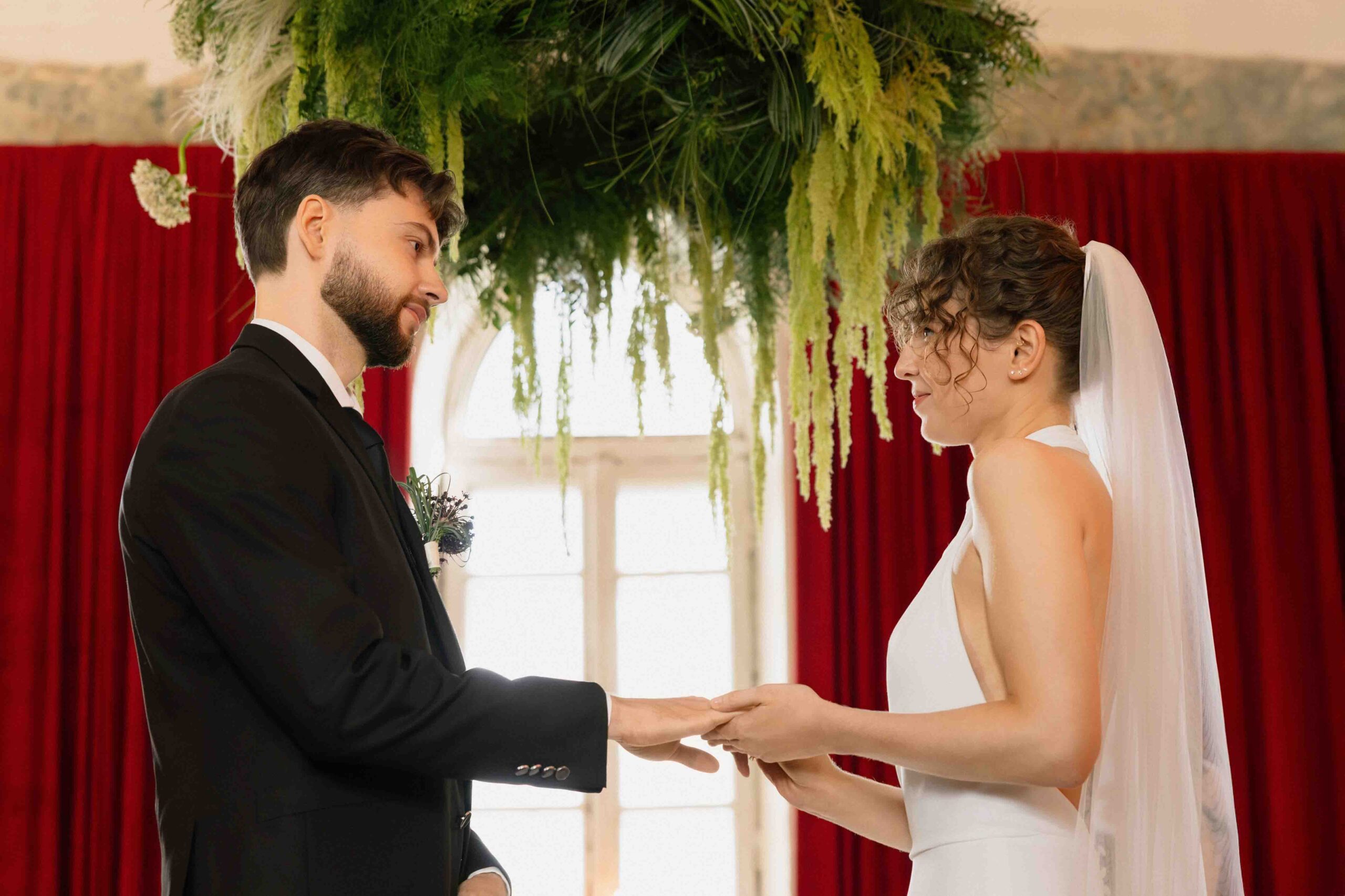 wedding ceremony exchancing rings burgundy backdrop