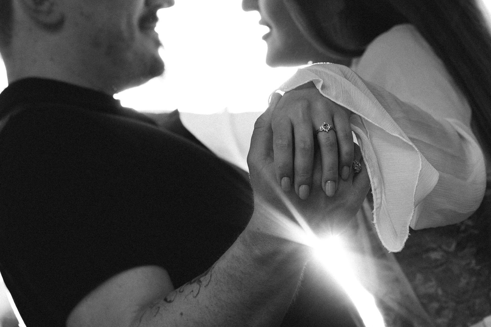 Backlit close-up of joined hands showing the new engagement ring.
