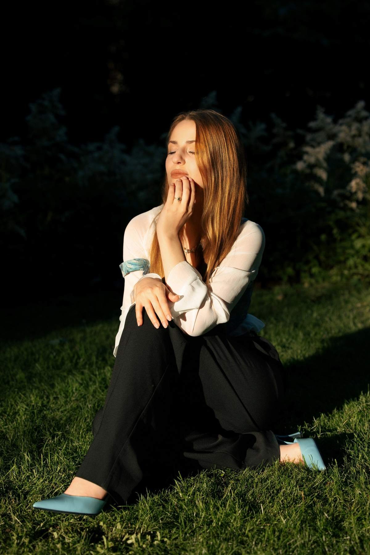 Brigita sitting alone on the grass, taking in the moment after the proposal.