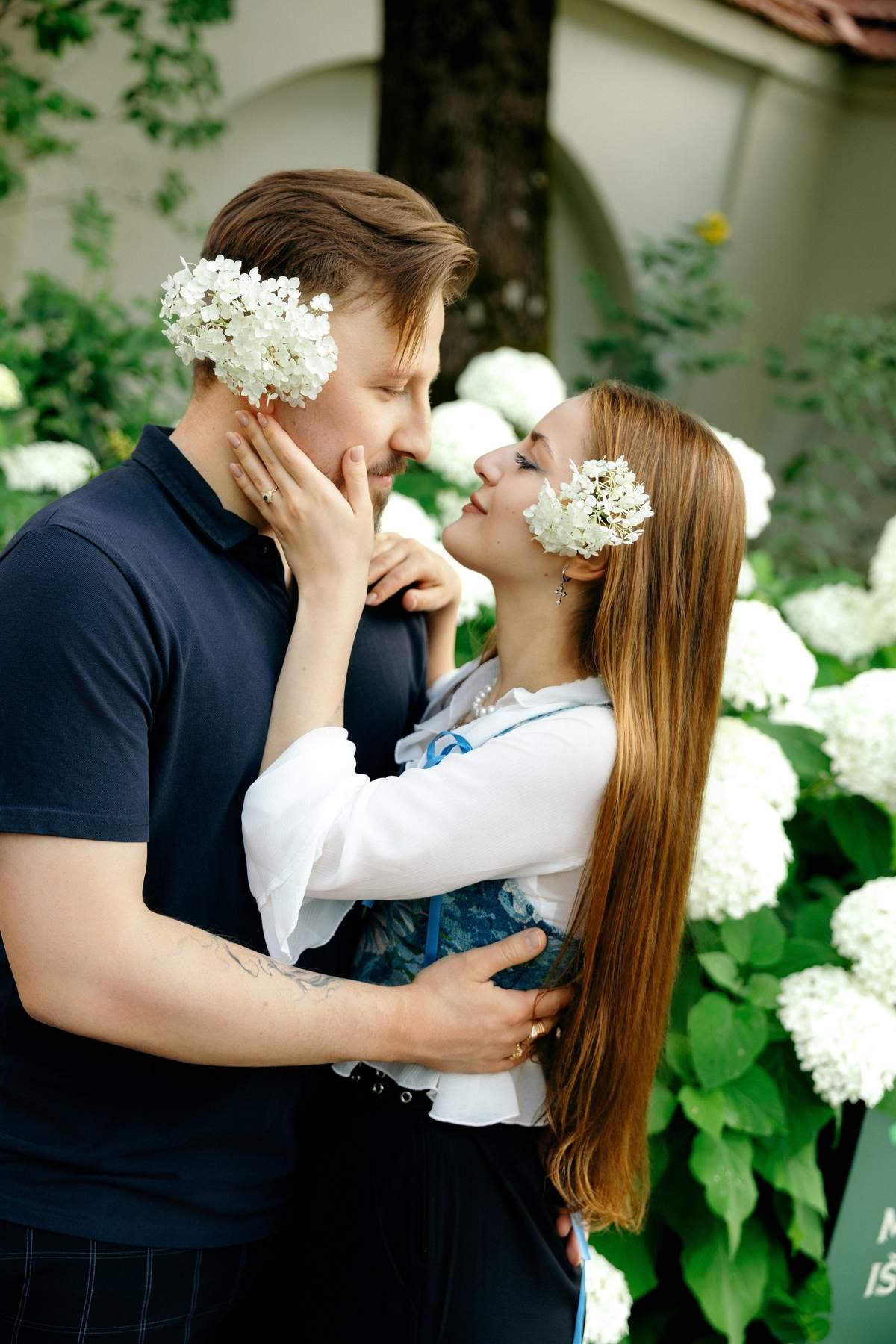 Couple portrait among blooming white hydrangeas in the garden.