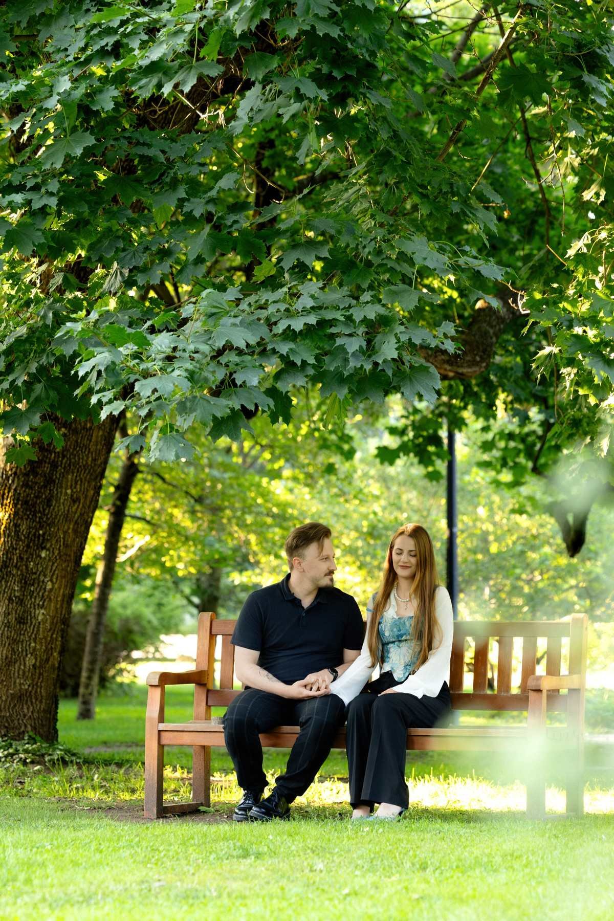 Brigita and Evaldas sitting together on a park bench in Bernardinų Garden, Vilnius, just before the surprise proposal.