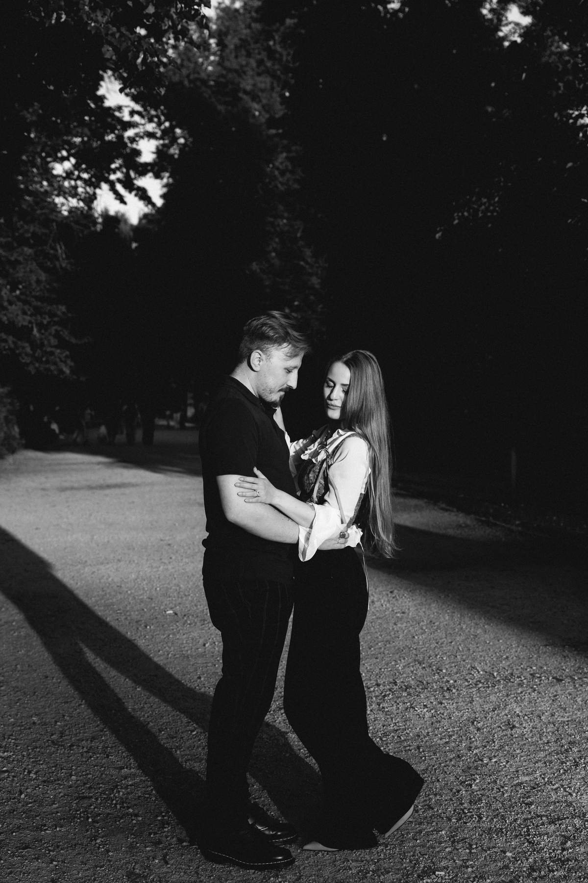 Black and white photo of the couple walking down a tree-lined path.