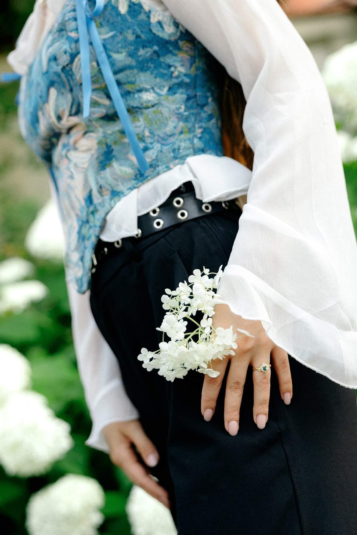 Detail shot of Brigita's blue floral corset outfit with a white flower.