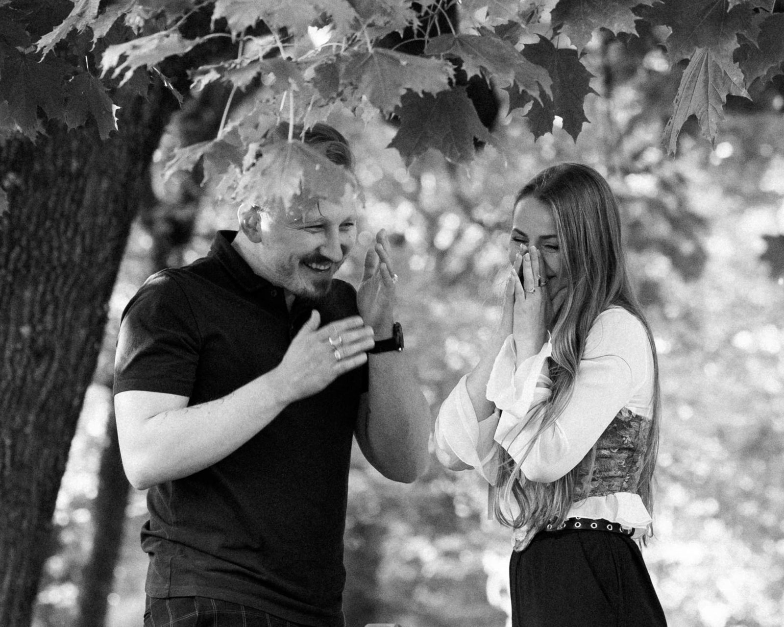 Evaldas presenting the engagement ring while still kneeling on the park bench.