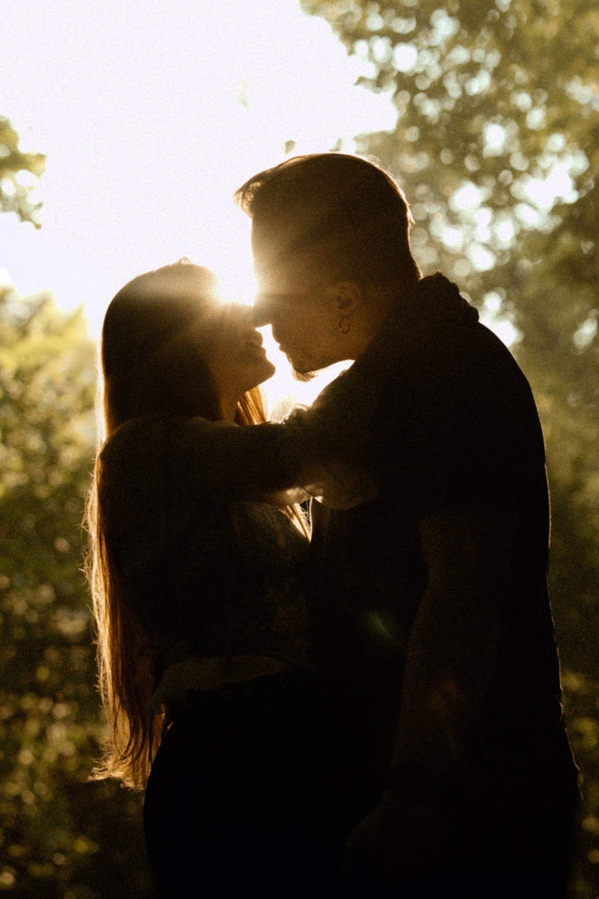 Golden hour silhouette of the couple kissing in the park in Vilnius.