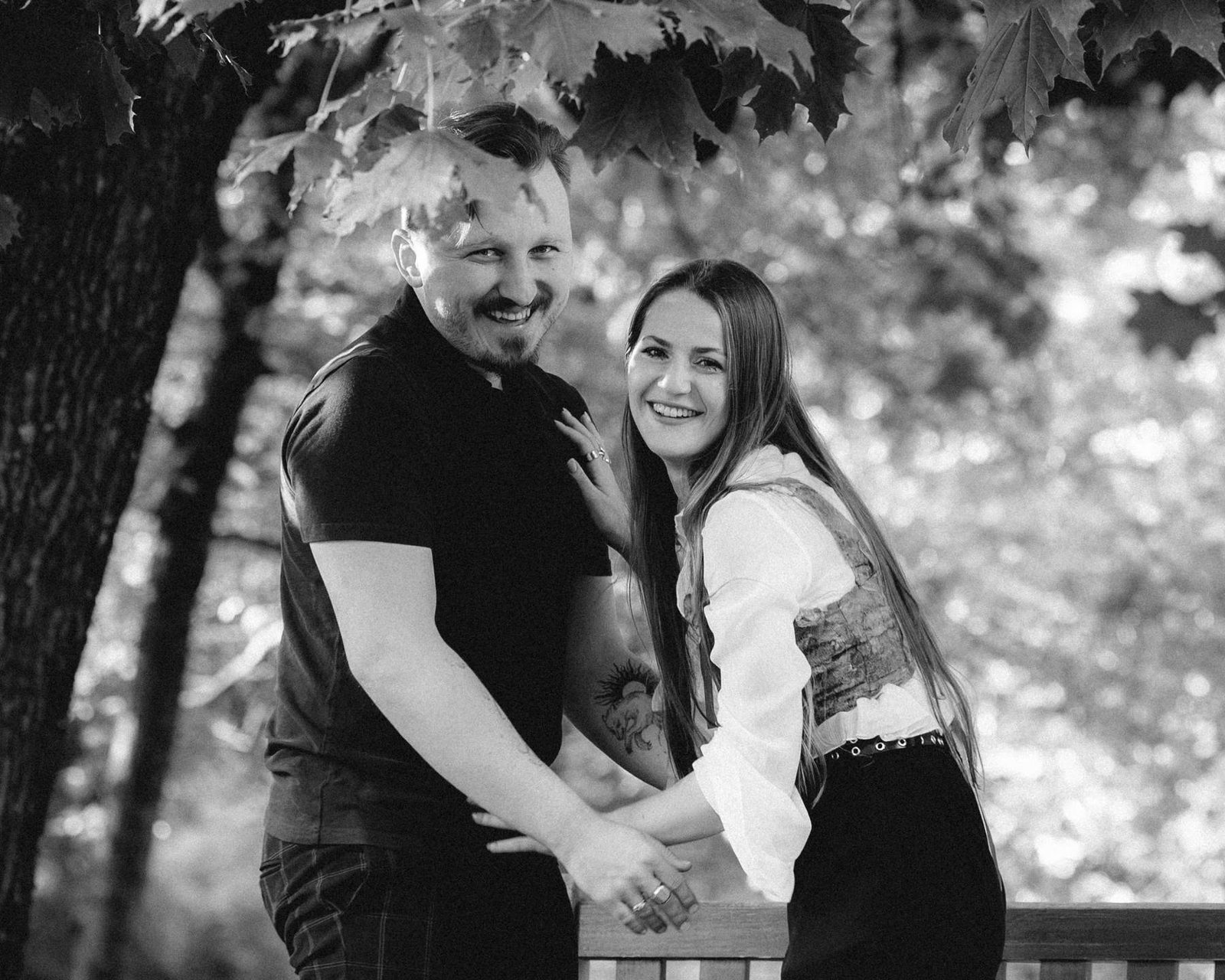 Newly engaged couple standing hand in hand in the park, black and white portrait.