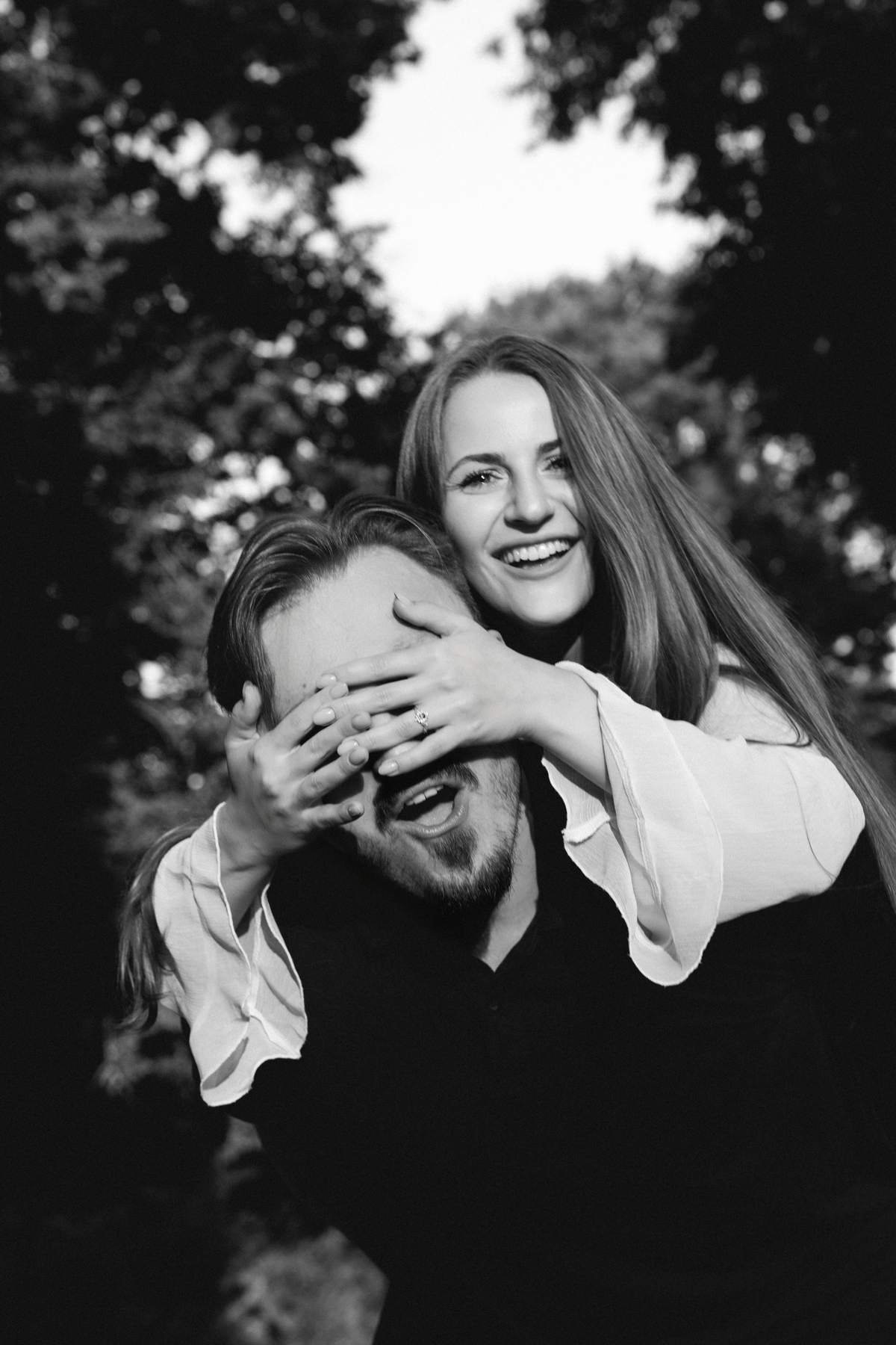 Couple standing together under a wooden pergola in Bernardinų Garden.