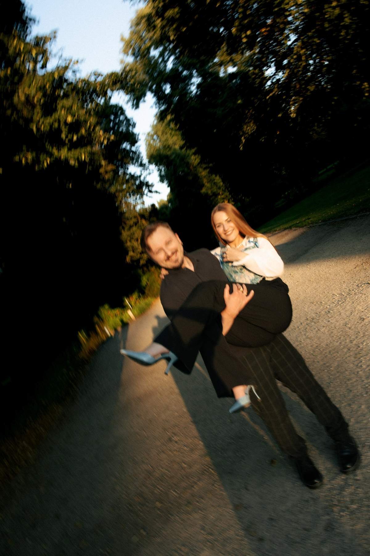 Playful piggyback moment between the newly engaged couple on the garden path.