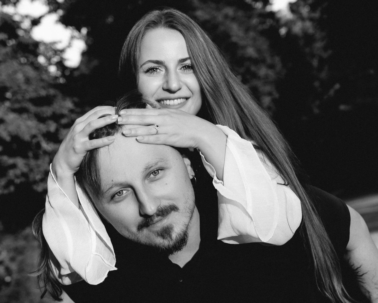Playful black and white portrait, Brigita with her arms wrapped around Evaldas's head.