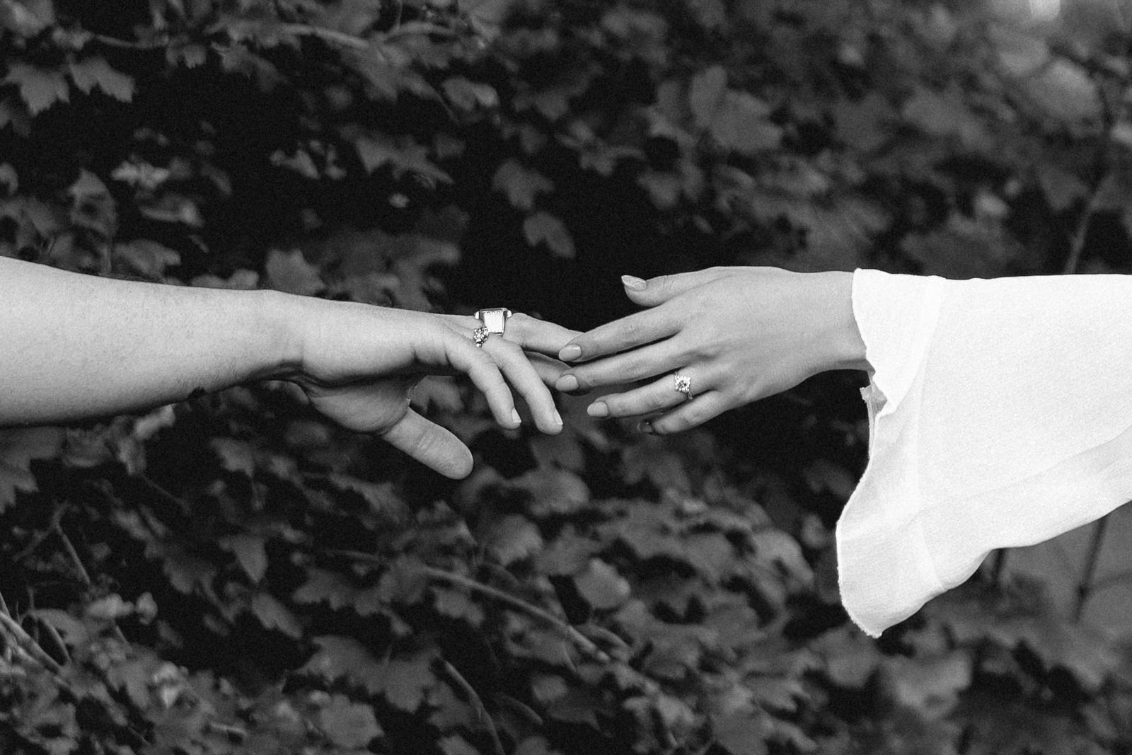 Black and white close-up of the couple reaching for each other's hands.