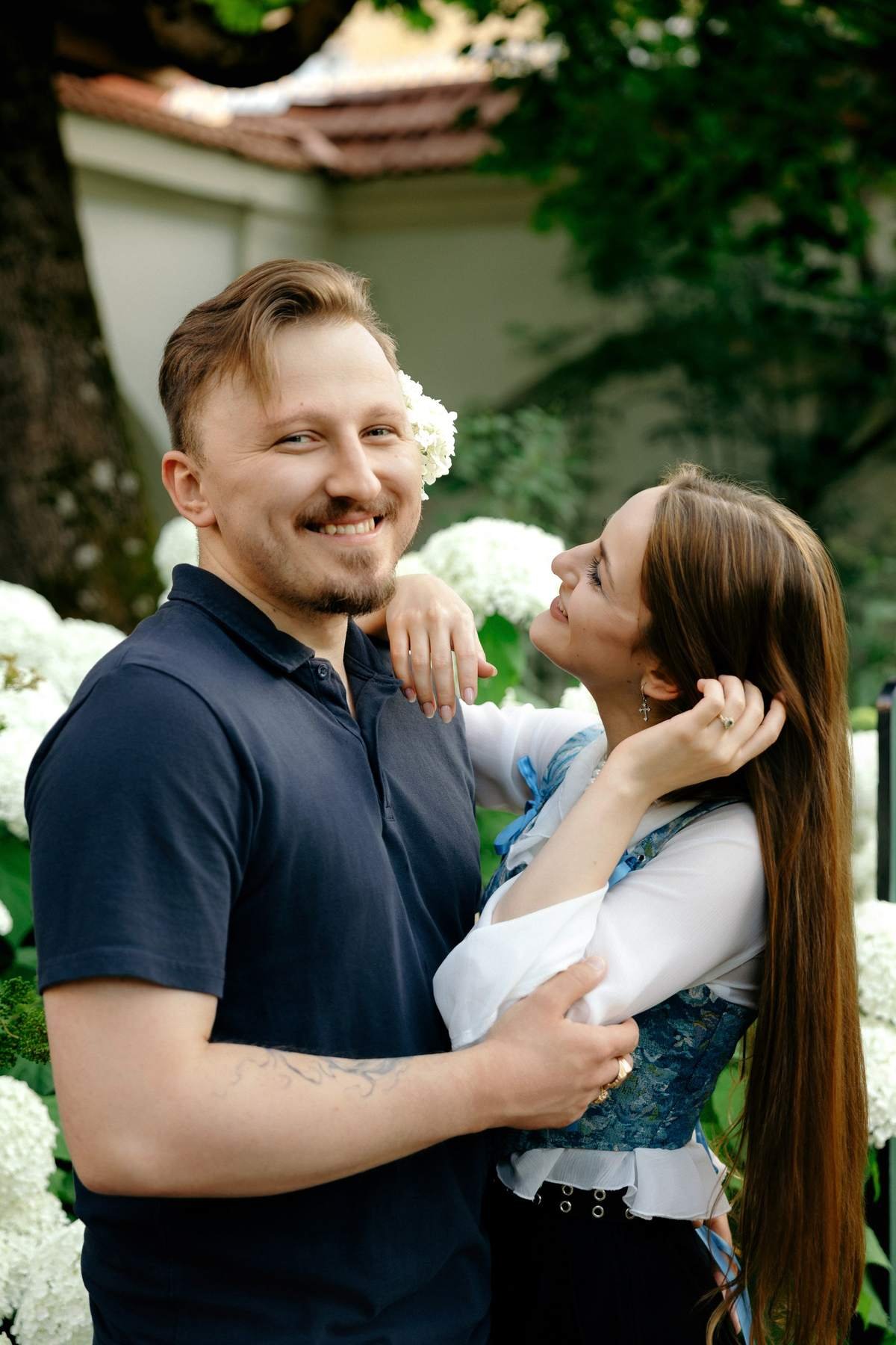 Smiling couple embracing near an old garden wall in Vilnius.