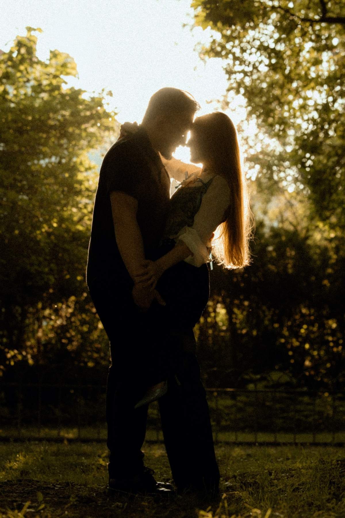 Sunset engagement portrait of the couple embracing in golden light.