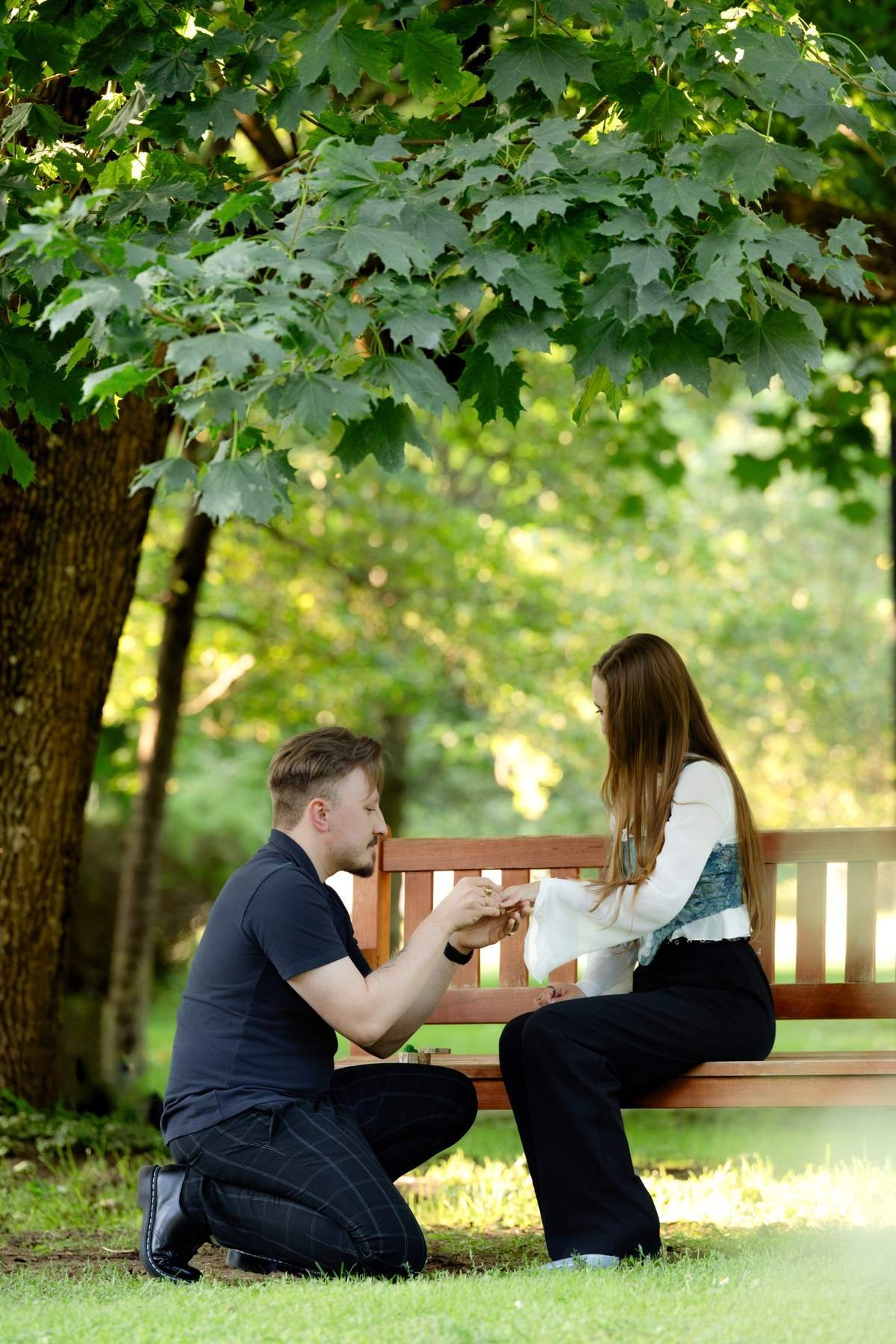 Wide shot of the surprise proposal under the trees at Bernardinų Garden in Vilnius.