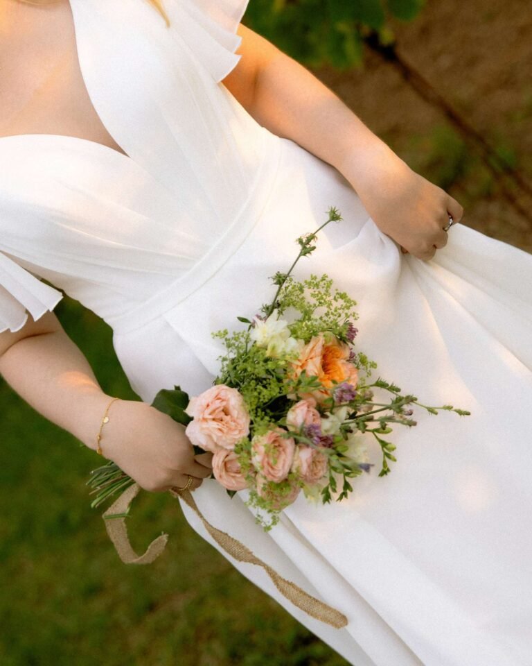 Bride holding a bouquet of peach roses and wildflowers